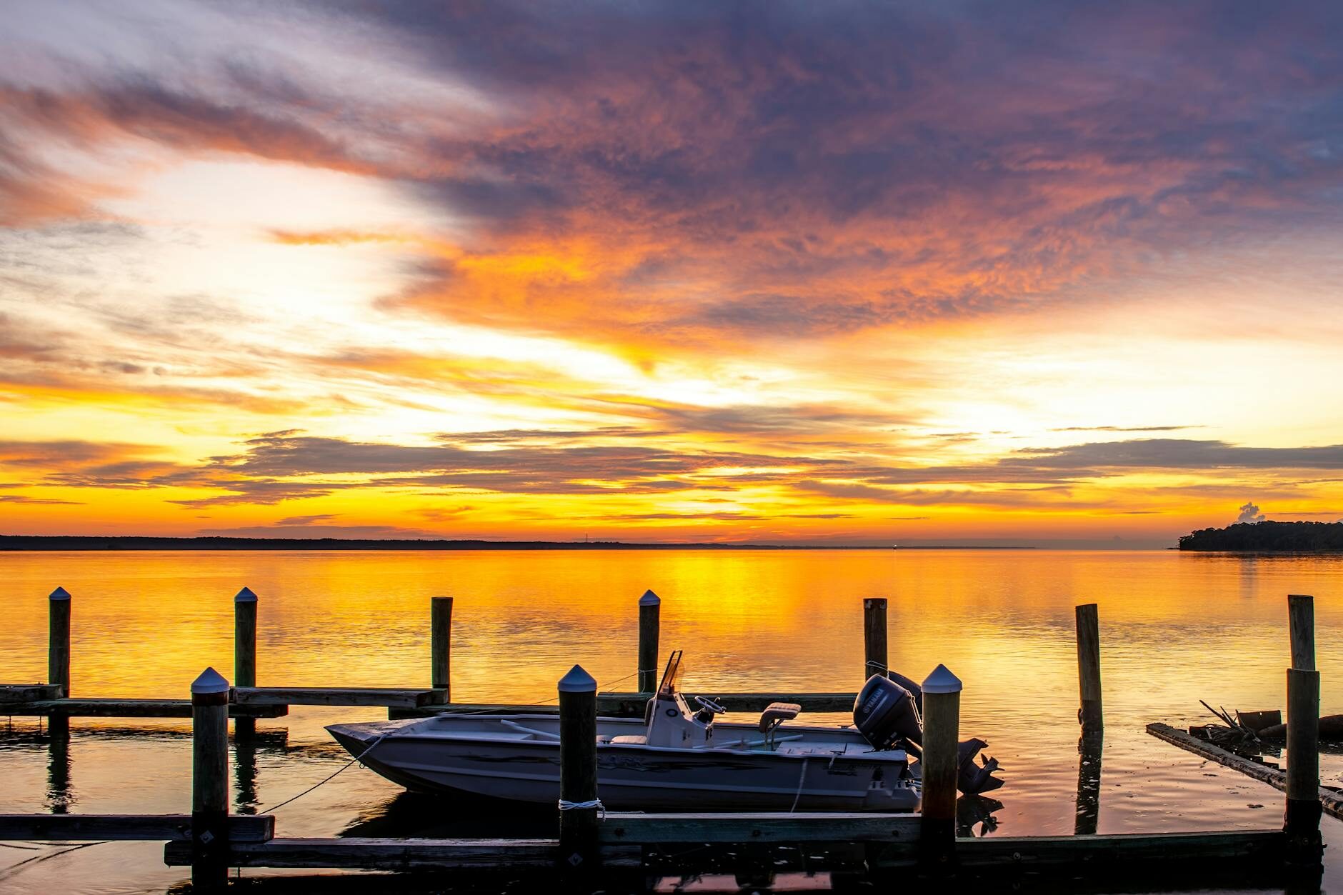 Gulf Coast sunset over calm water with a boat tied to a dock